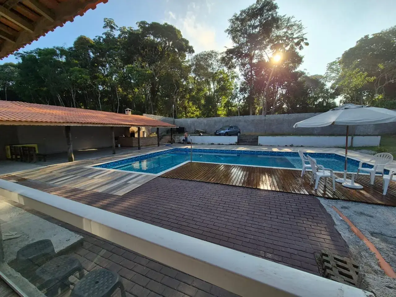 Piscina do sítio com o sol se pondo atrás das árvores